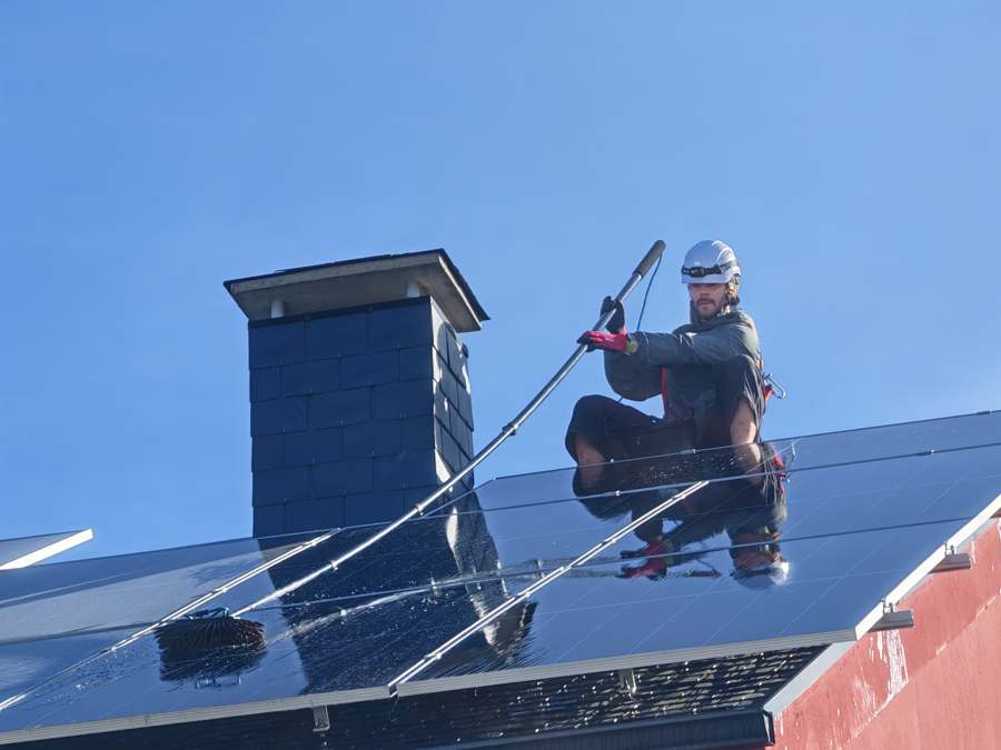 Técnico limpiando placa solar en altura
